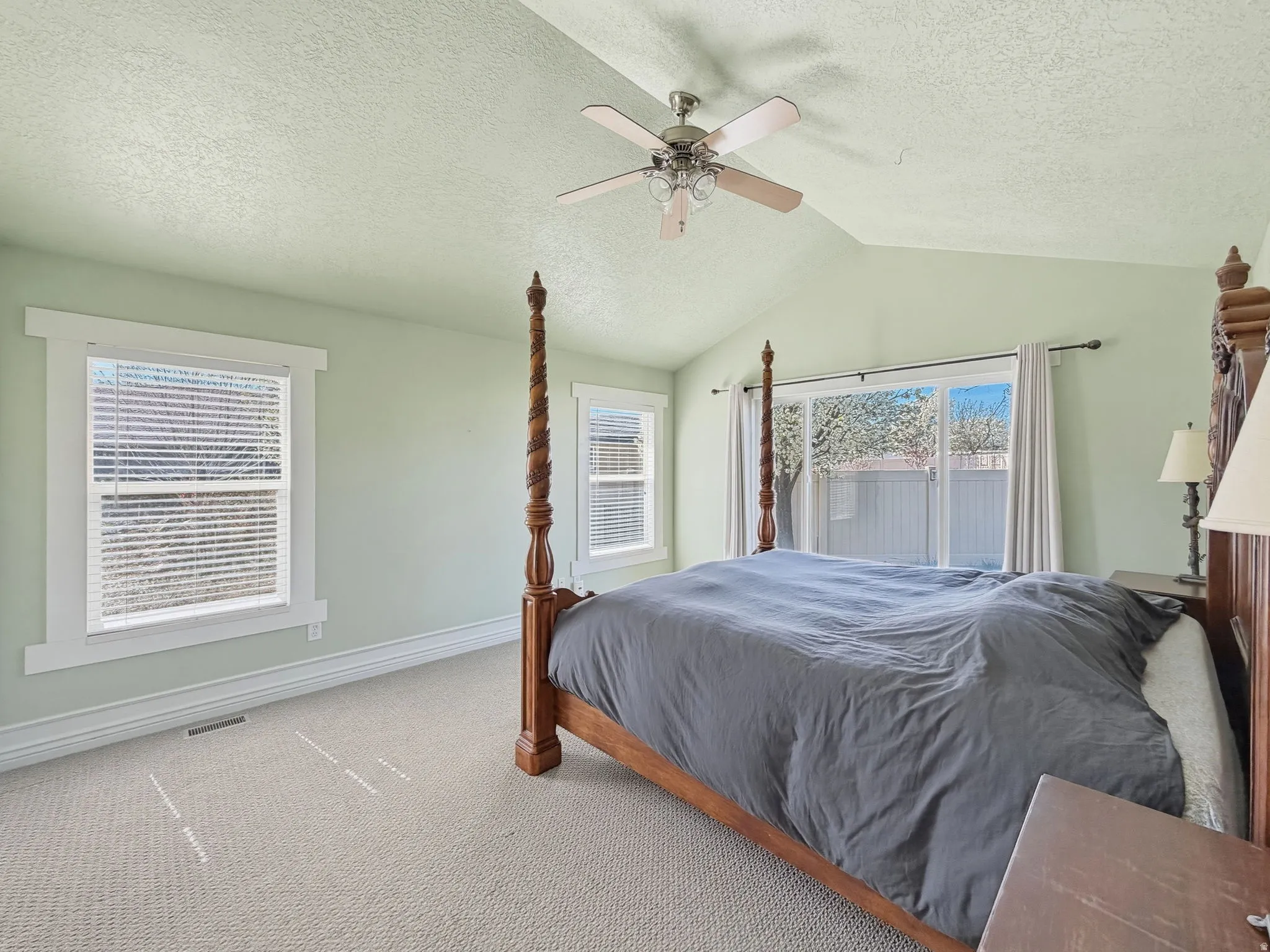 Bedroom featuring a textured ceiling, light carpet, and ceiling fan