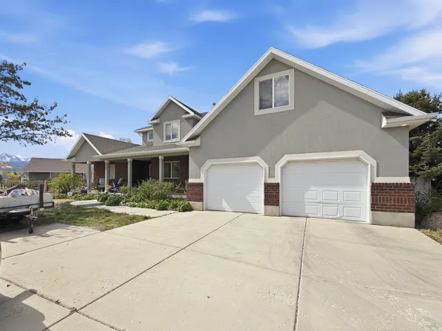 View of front of property with brick siding, driveway, a porch, and stucco siding