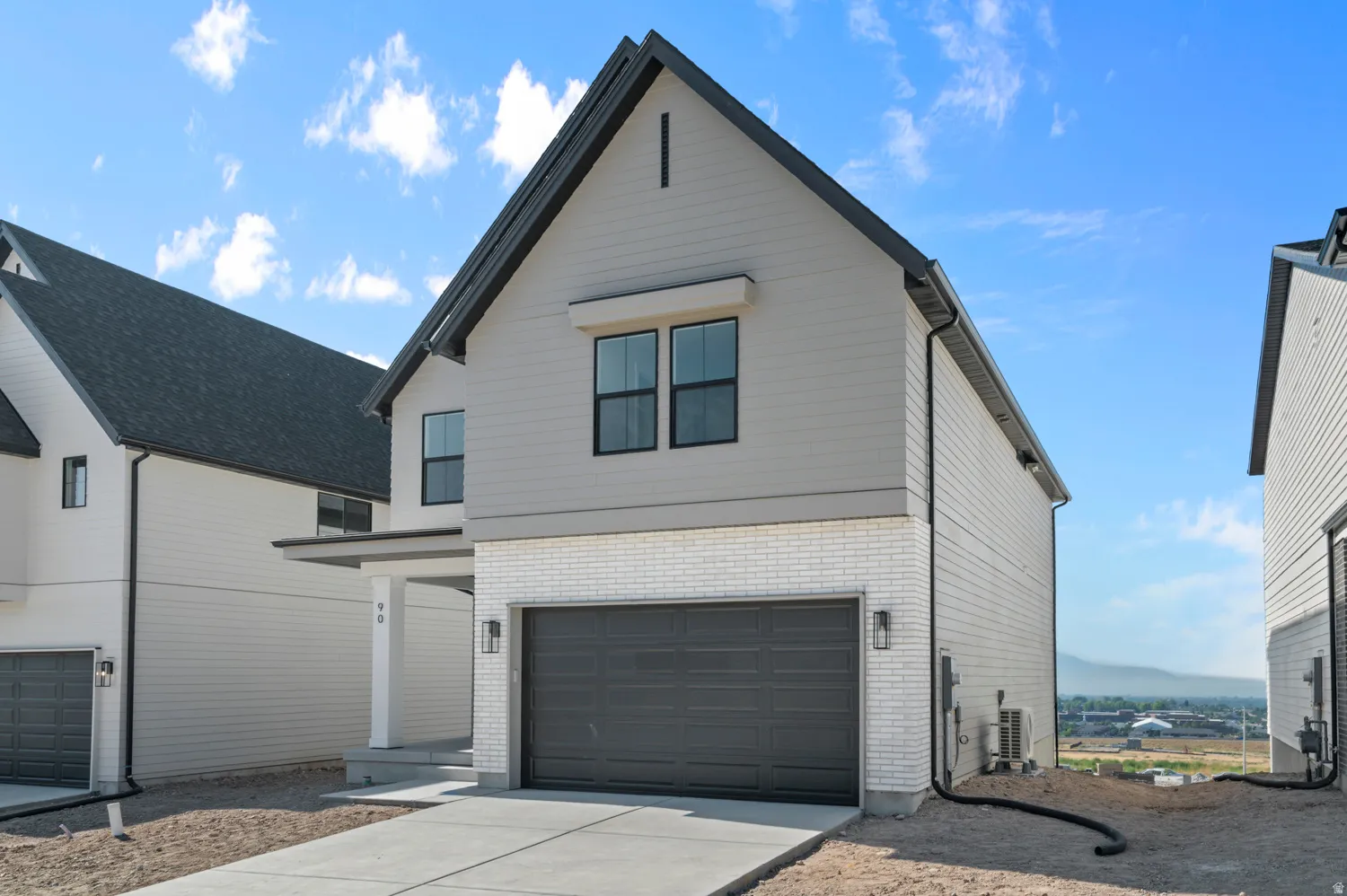 View of front facade with brick siding, driveway, and a garage