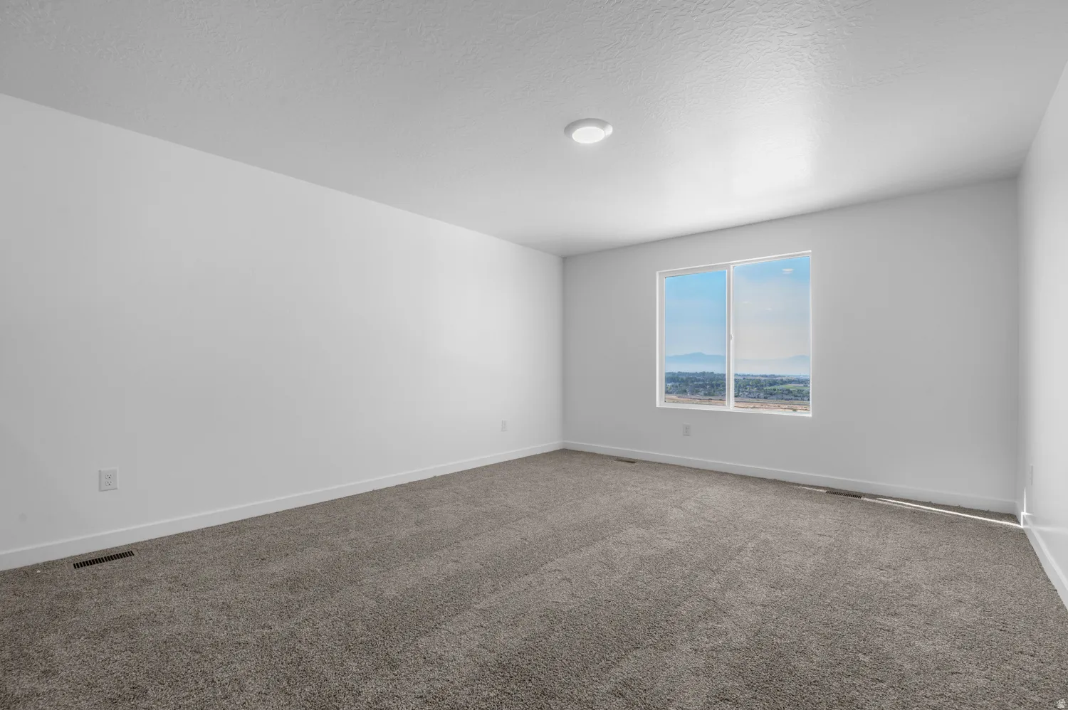 Unfurnished room featuring dark colored carpet and a textured ceiling