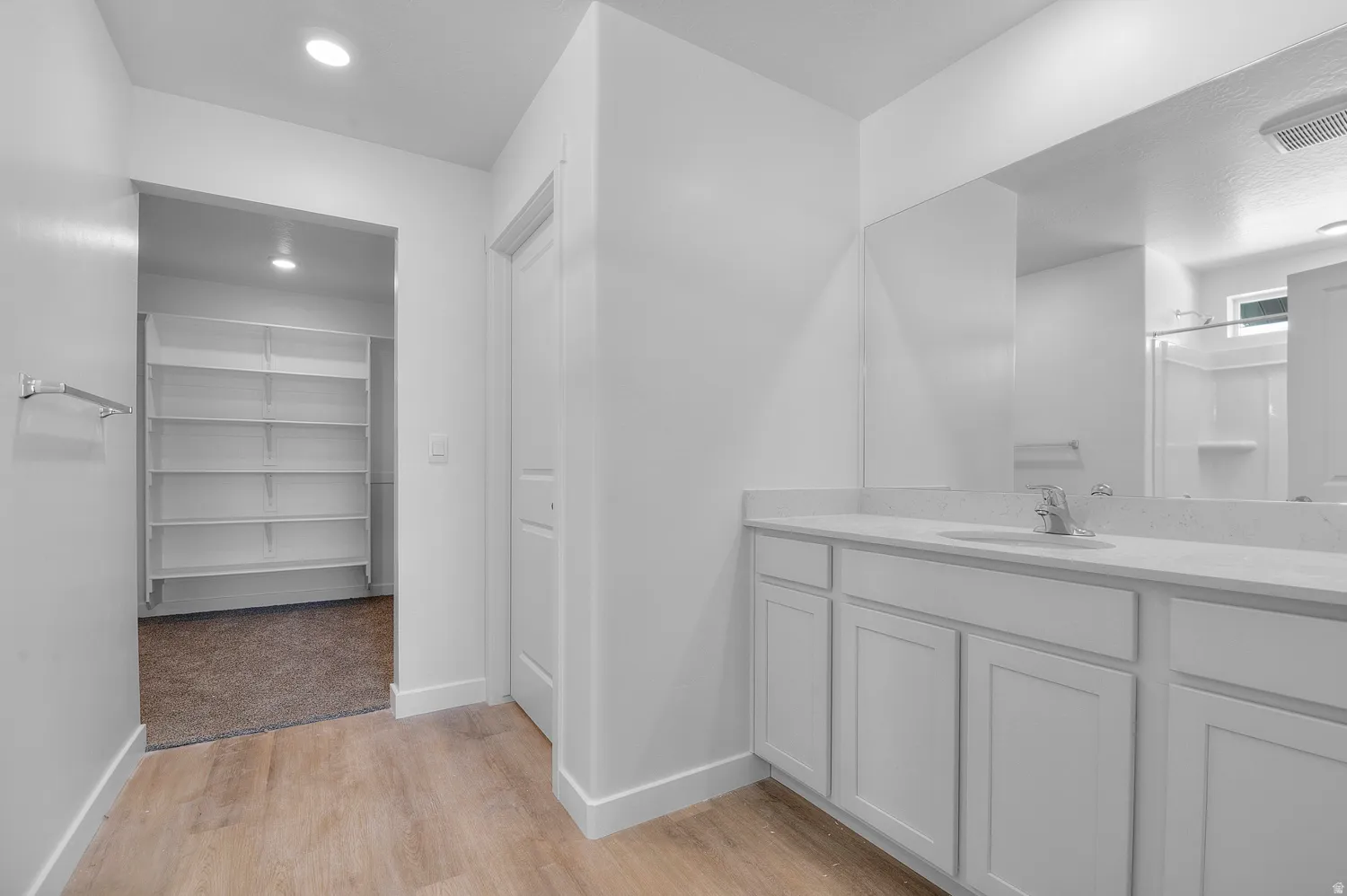 Full bathroom with a walk in closet, vanity, light wood-style flooring, a shower stall, and recessed lighting