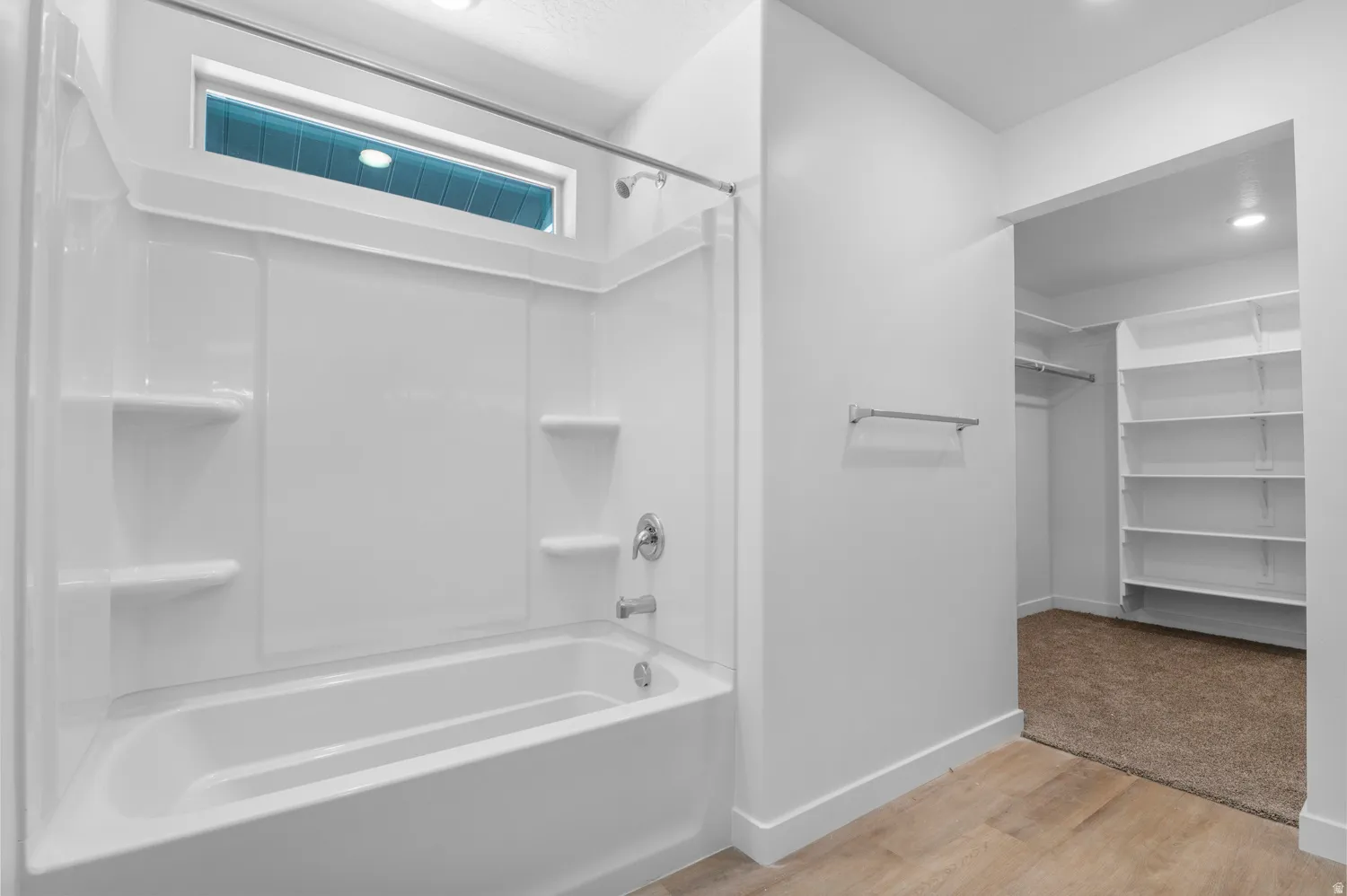 Bathroom featuring a walk in closet, light wood finished floors, and shower / bathtub combination