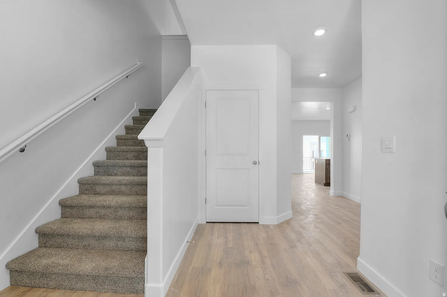 Stairs featuring wood finished floors and recessed lighting