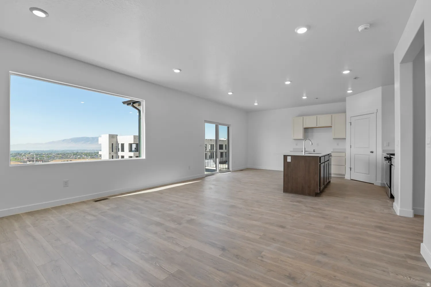 Kitchen with open floor plan, a kitchen island with sink, two tone color scheme, light wood-style flooring, and a mountain view