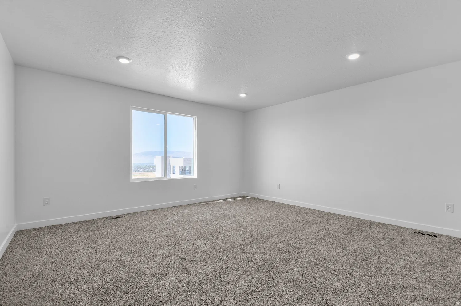 Spare room with carpet floors, a textured ceiling, and recessed lighting