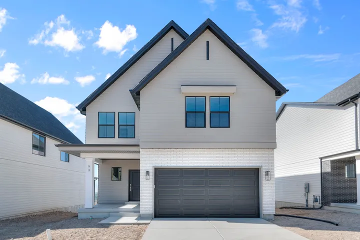 View of front facade featuring brick siding, concrete driveway, an attached garage, and covered porch