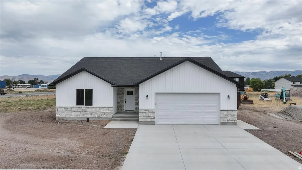 Modern inspired farmhouse featuring a mountain view, stone siding, a garage, and concrete driveway