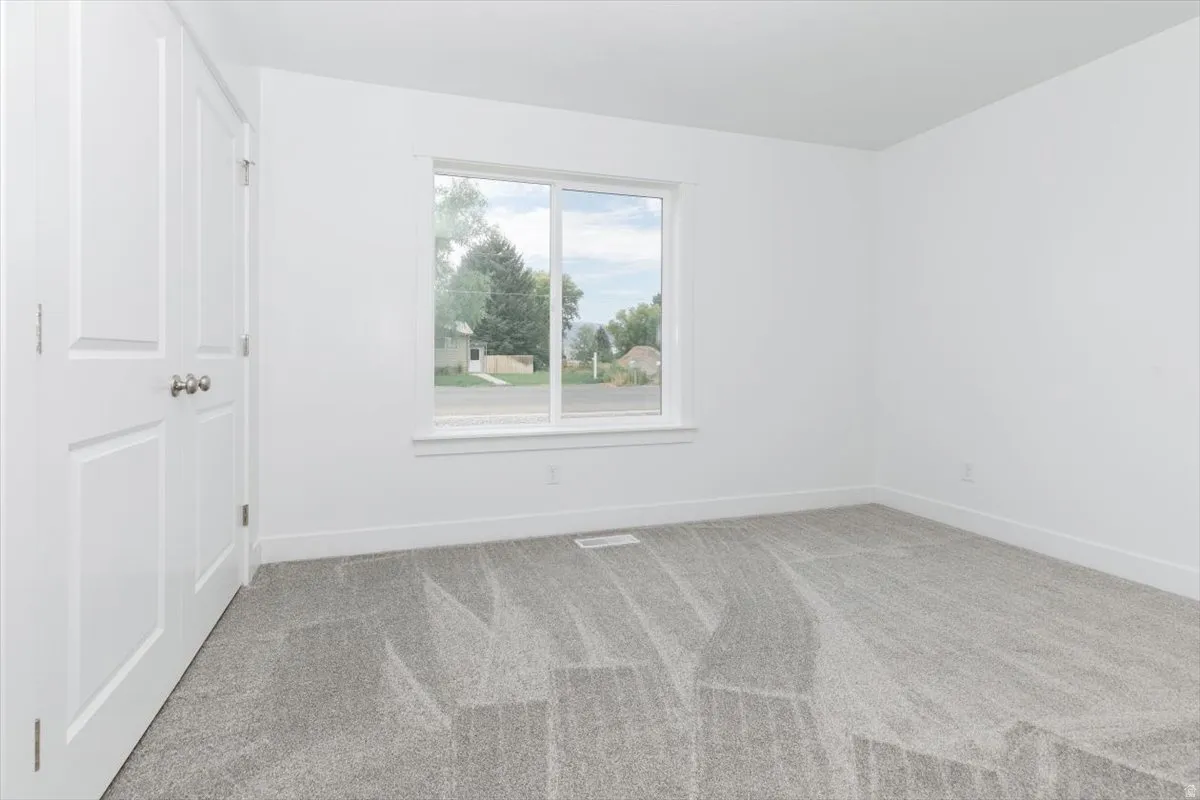 Unfurnished room with light colored carpet and baseboards