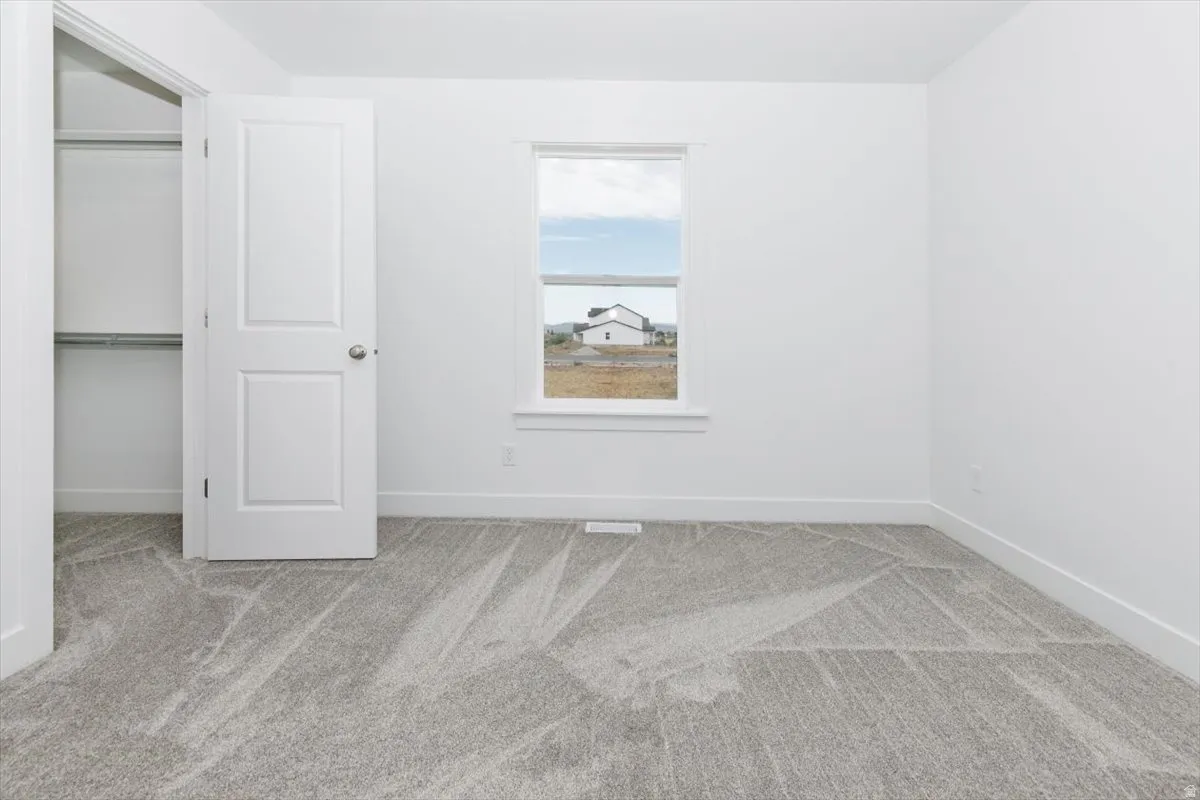 Unfurnished bedroom featuring light colored carpet and baseboards
