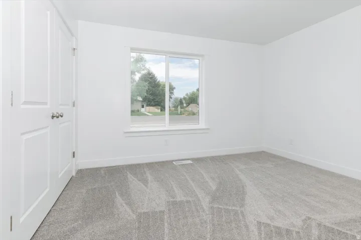 Unfurnished room with light colored carpet and baseboards