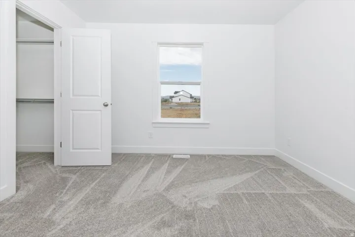Unfurnished bedroom featuring light colored carpet and baseboards