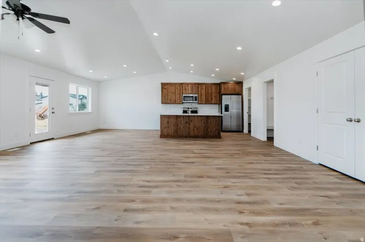 Kitchen featuring open floor plan, lofted ceiling, stainless steel appliances, light countertops, and tasteful backsplash
