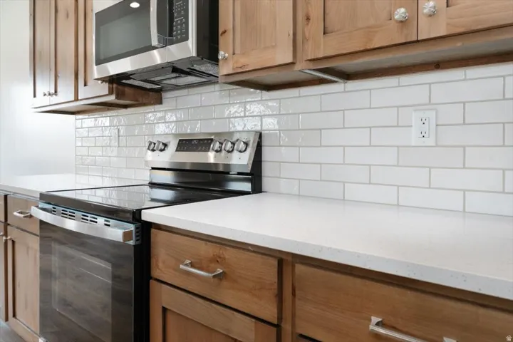 Kitchen with stainless steel appliances, light stone countertops, and decorative backsplash