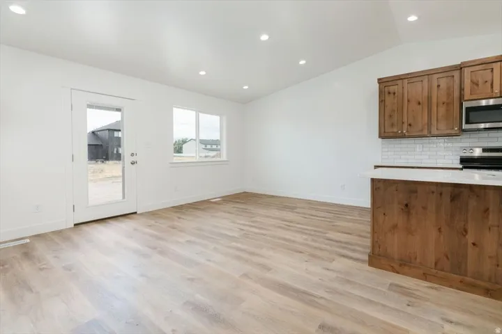 Unfurnished living room with vaulted ceiling, recessed lighting, and light wood finished floors