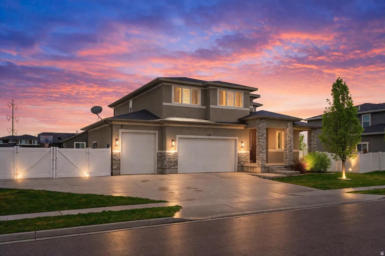 AI Enhanced Twilight Photo - Prairie-style home with a gate, stone siding, stucco siding, concrete driveway, and a garage