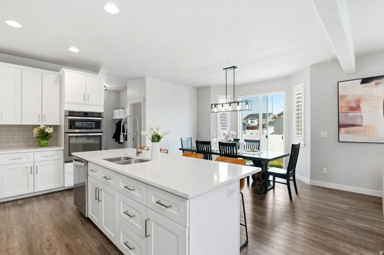 Kitchen with white cabinets, a kitchen bar, dark wood-type flooring, and beamed ceiling