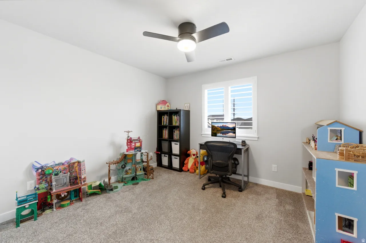 Home office with light carpet and ceiling fan