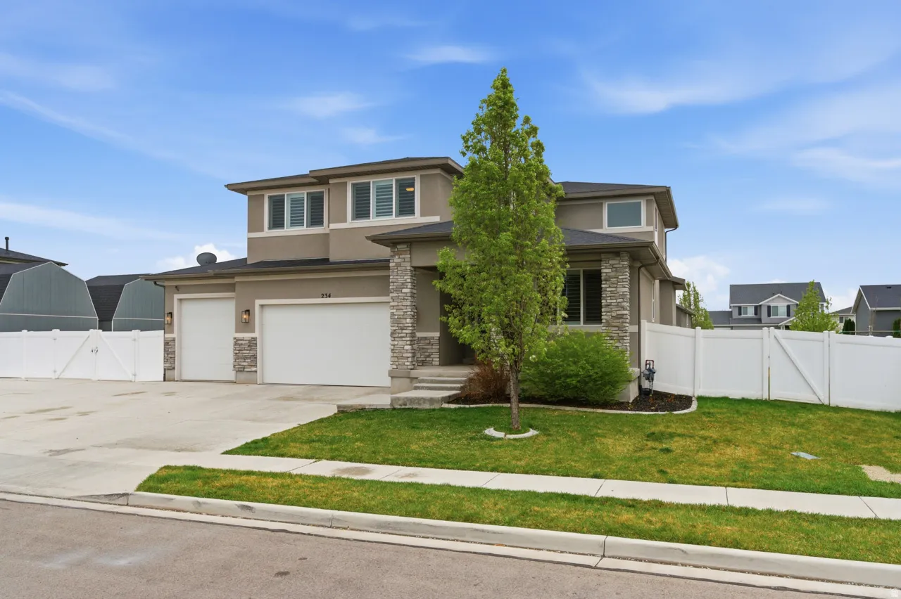 Prairie-style home with a gate, stucco siding, stone siding, concrete driveway, and an attached garage