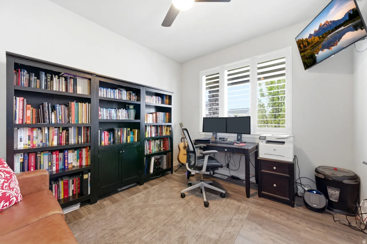 Home office with light wood-type flooring and ceiling fan