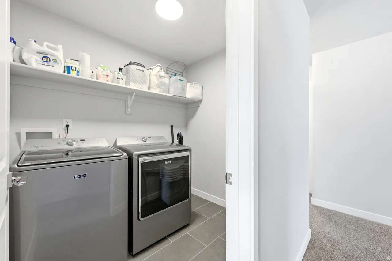 Laundry area featuring light tile patterned flooring and separate washer and dryer