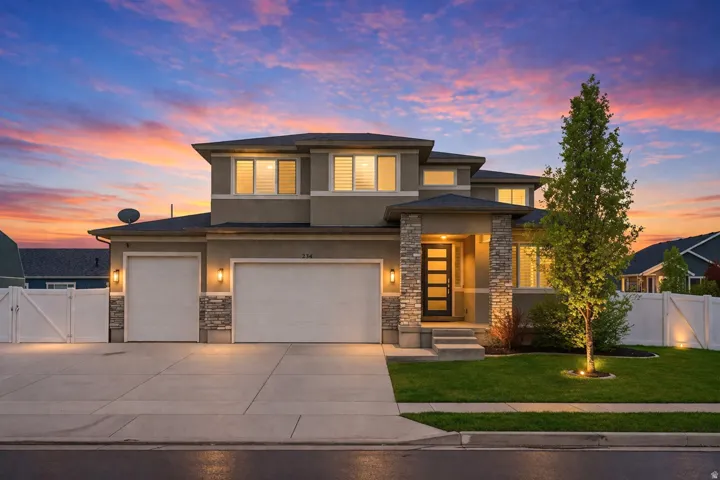 AI Enhanced Twilight Photo - Prairie-style house with a gate, stone siding, stucco siding, and driveway
