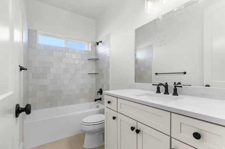 Bathroom featuring vanity, washtub / shower combination, and light tile patterned flooring