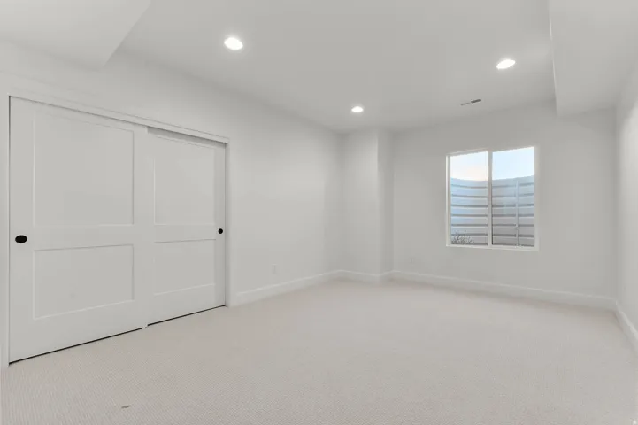 Unfurnished bedroom with recessed lighting, light carpet, and a closet