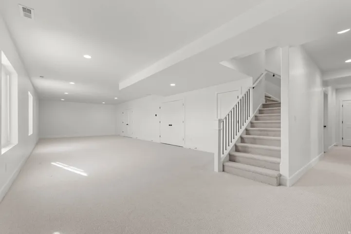 Finished below grade area featuring recessed lighting and light colored carpet