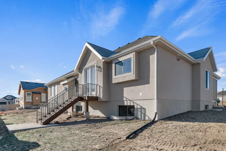 View of side of property featuring stucco siding and roof with shingles