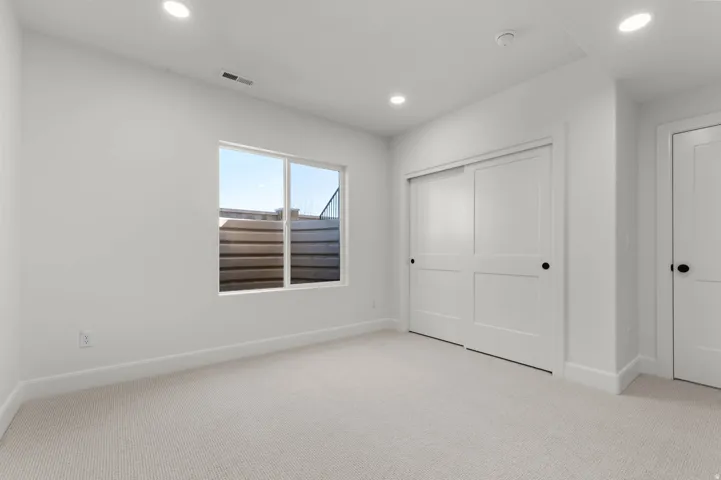Unfurnished bedroom with light carpet, a closet, and recessed lighting