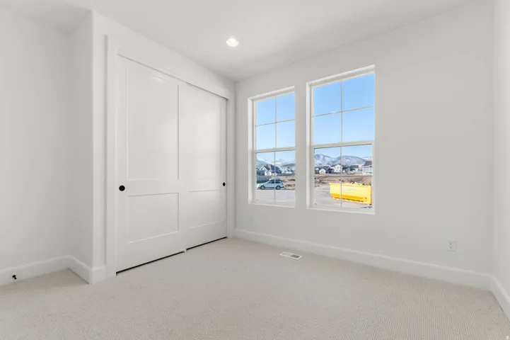 Unfurnished bedroom with light colored carpet, a closet, a mountain view, and recessed lighting