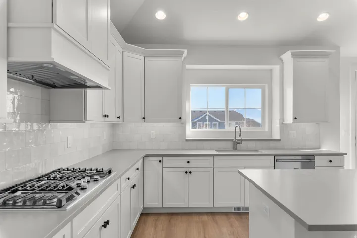 Kitchen with white cabinetry, stainless steel appliances, light wood-style floors, and recessed lighting
