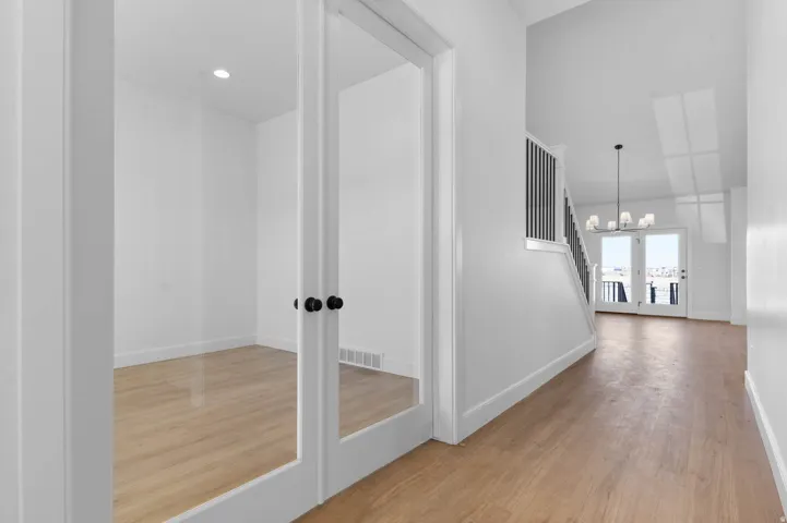 Corridor with light wood-type flooring and hanging lights