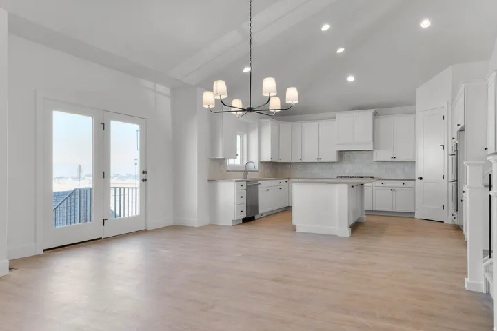 Kitchen featuring a kitchen island, white cabinets, lofted ceiling, suspended lighting, and decorative backsplash
