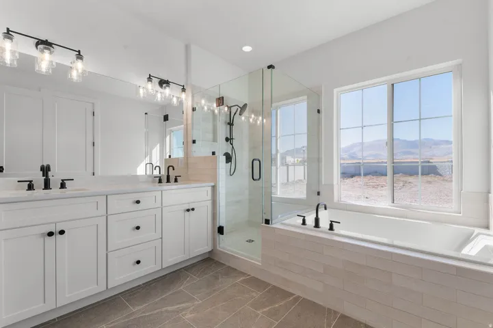 Bathroom with double vanity, a garden tub, a shower stall, a mountain view, and recessed lighting