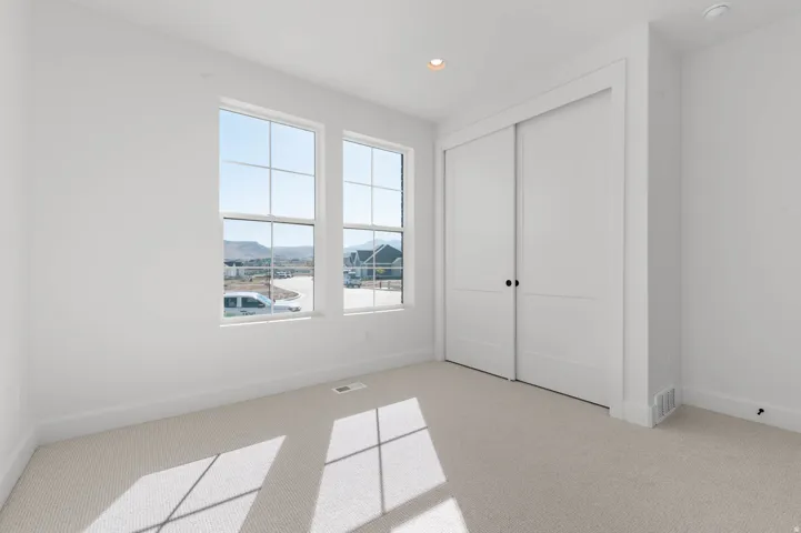 Unfurnished bedroom with recessed lighting, light colored carpet, a closet, and a mountain view