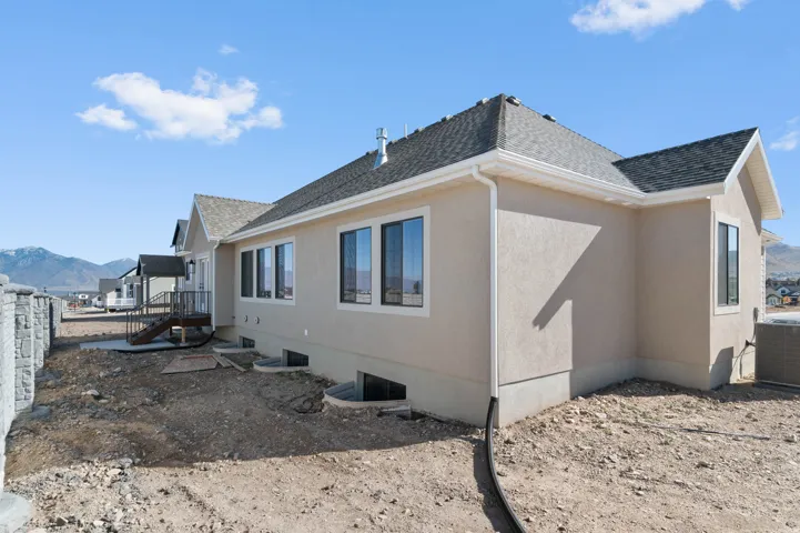 View of side of property with a shingled roof, a mountain view, and stucco siding
