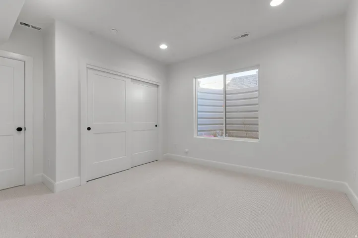Unfurnished bedroom featuring light carpet, recessed lighting, and a closet
