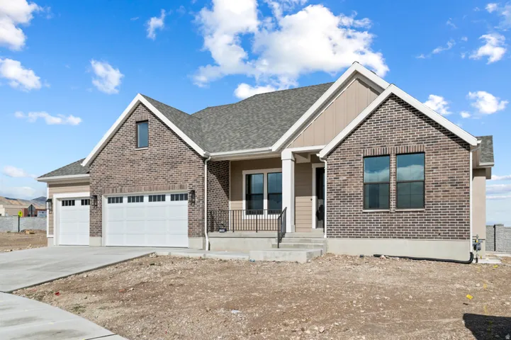 View of front of home with a porch, an attached garage, driveway, brick siding, and board and batten siding