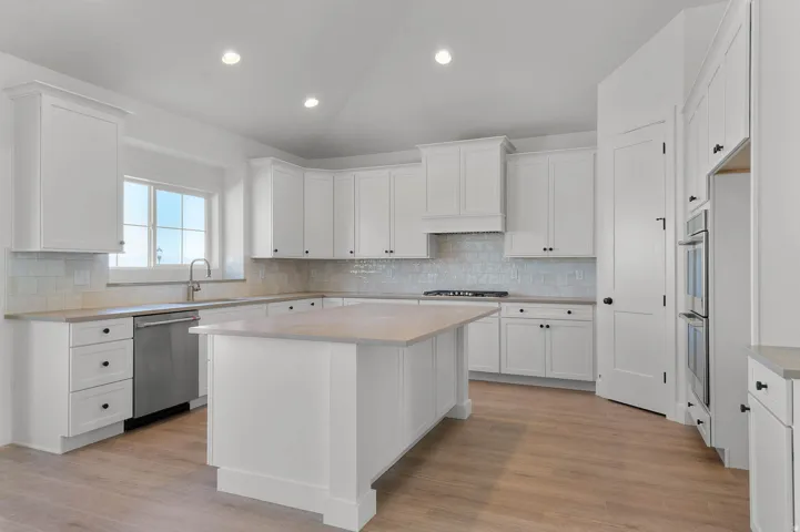 Kitchen with lofted ceiling, white cabinetry, stainless steel appliances, a center island, and recessed lighting