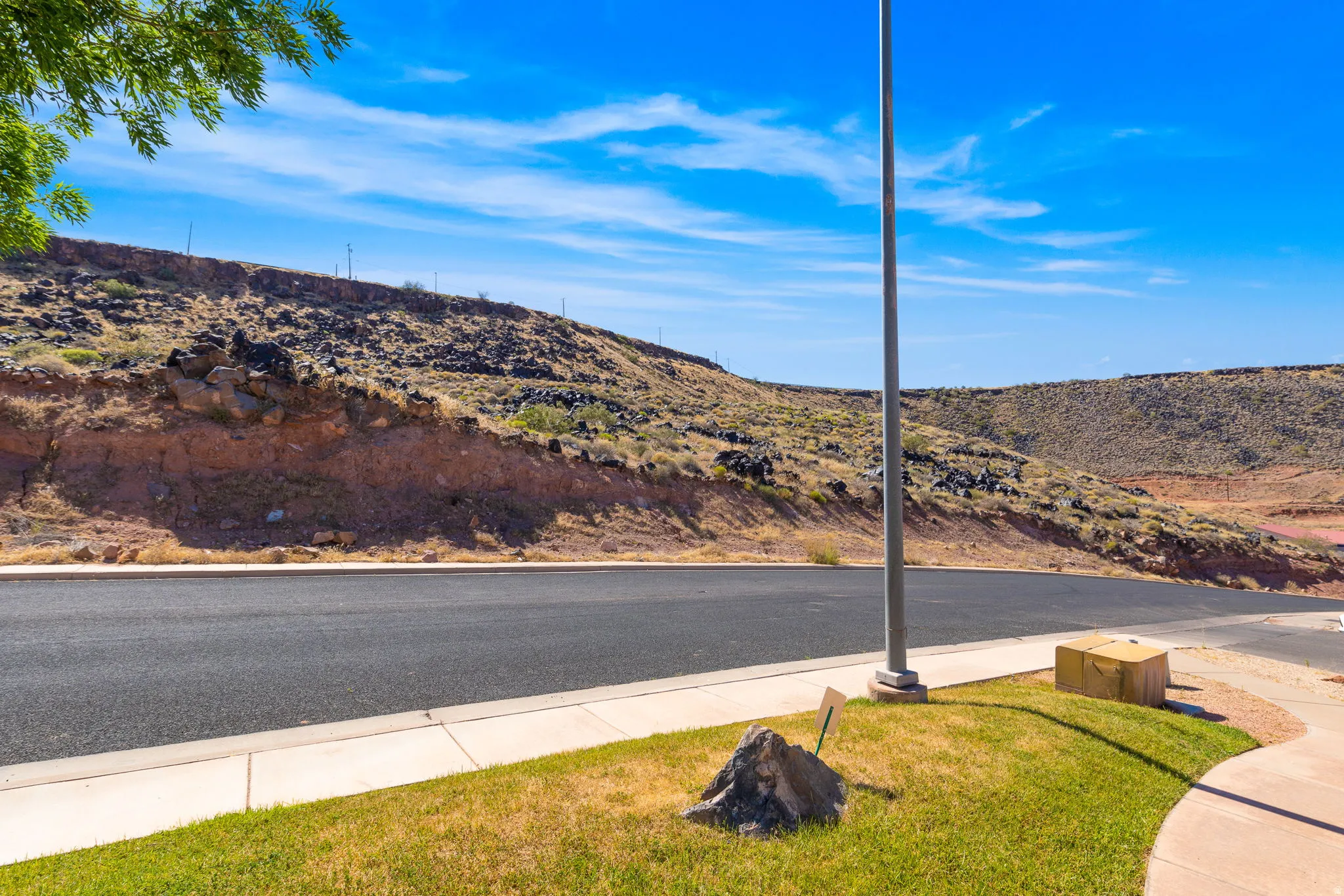 View of asphalt street featuring sidewalks, a mountain view, and curbs