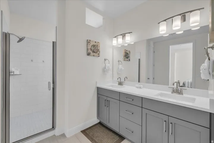 Bathroom with double vanity, a shower stall, and light tile patterned floors