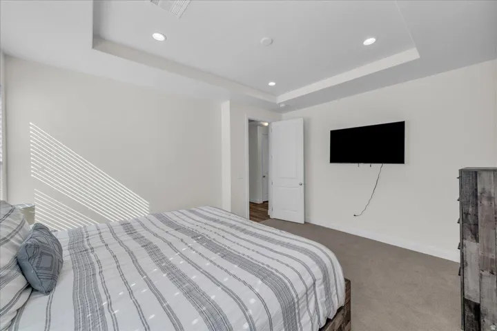 Carpeted bedroom featuring a tray ceiling and recessed lighting