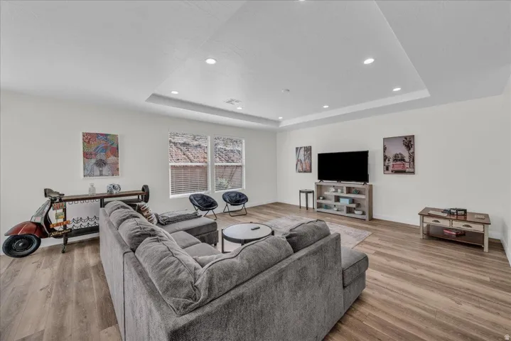 Living room with light wood-type flooring, recessed lighting, and a raised ceiling