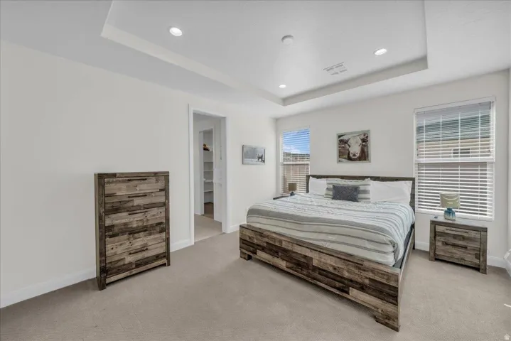 Bedroom with recessed lighting, light carpet, and a raised ceiling
