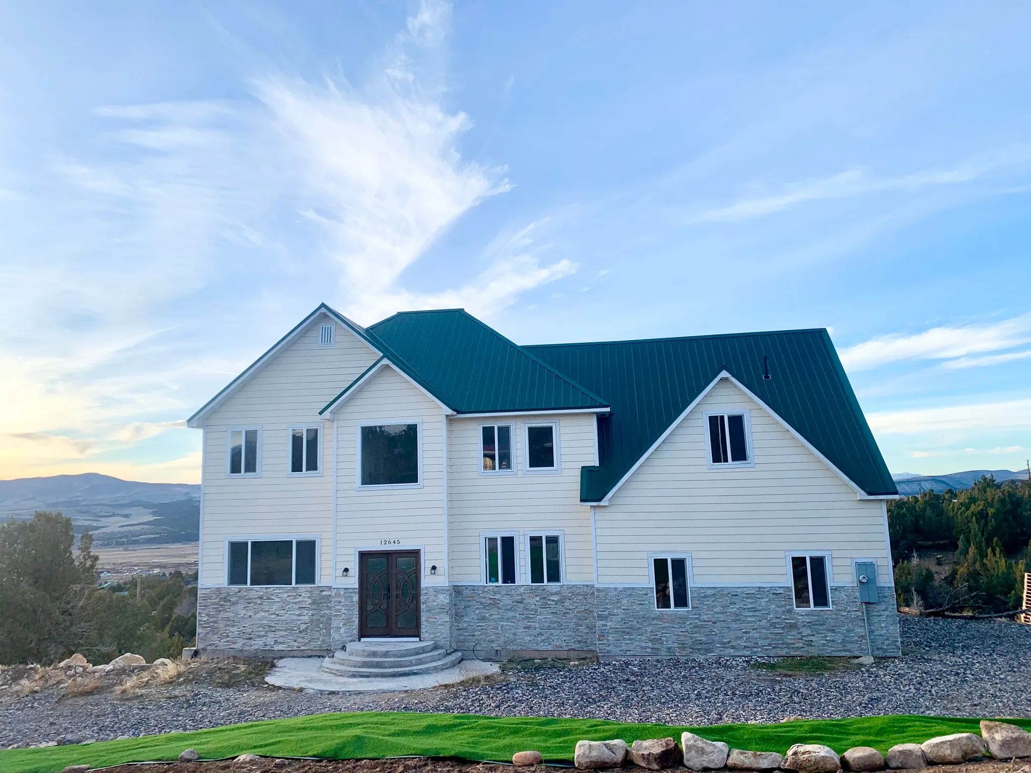 View of front of property with a mountain view, stone siding, and a metal roof