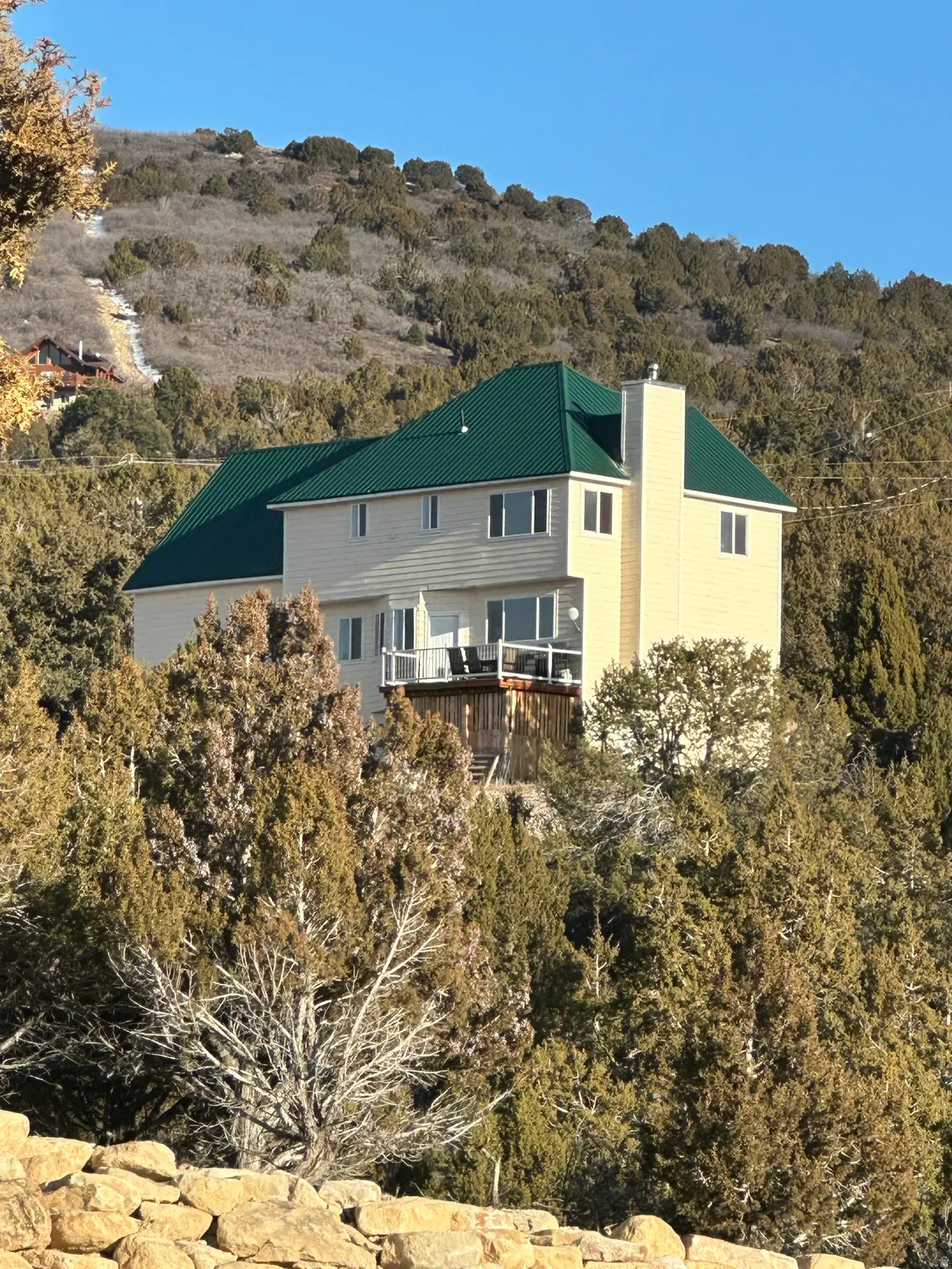 Back of house with a chimney, a metal roof, and a balcony