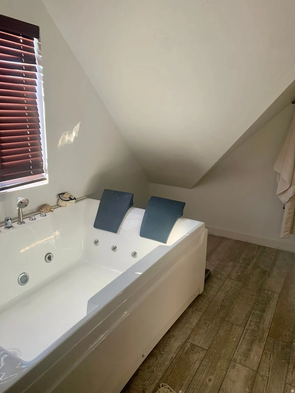 Bathroom featuring vaulted ceiling, hardwood / wood-style flooring, and a whirlpool tub