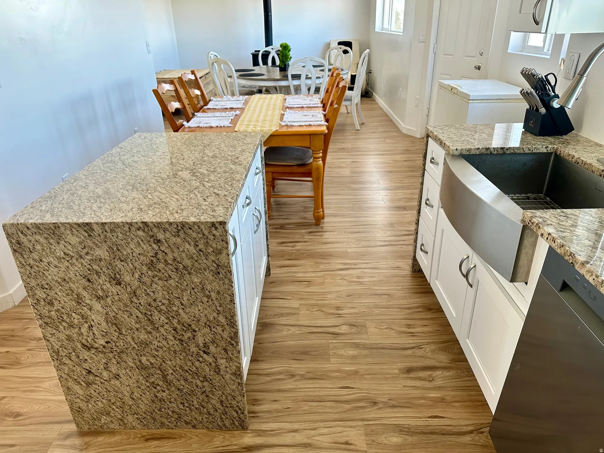 Kitchen featuring light stone counters, light wood finished floors, and dishwashing machine