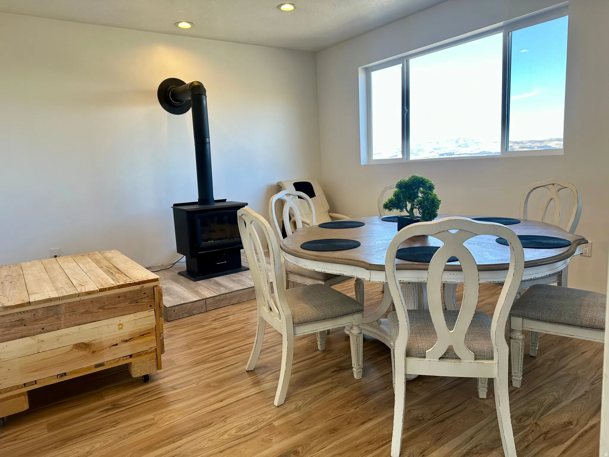 Dining space with a wood stove, light wood-style floors, and recessed lighting